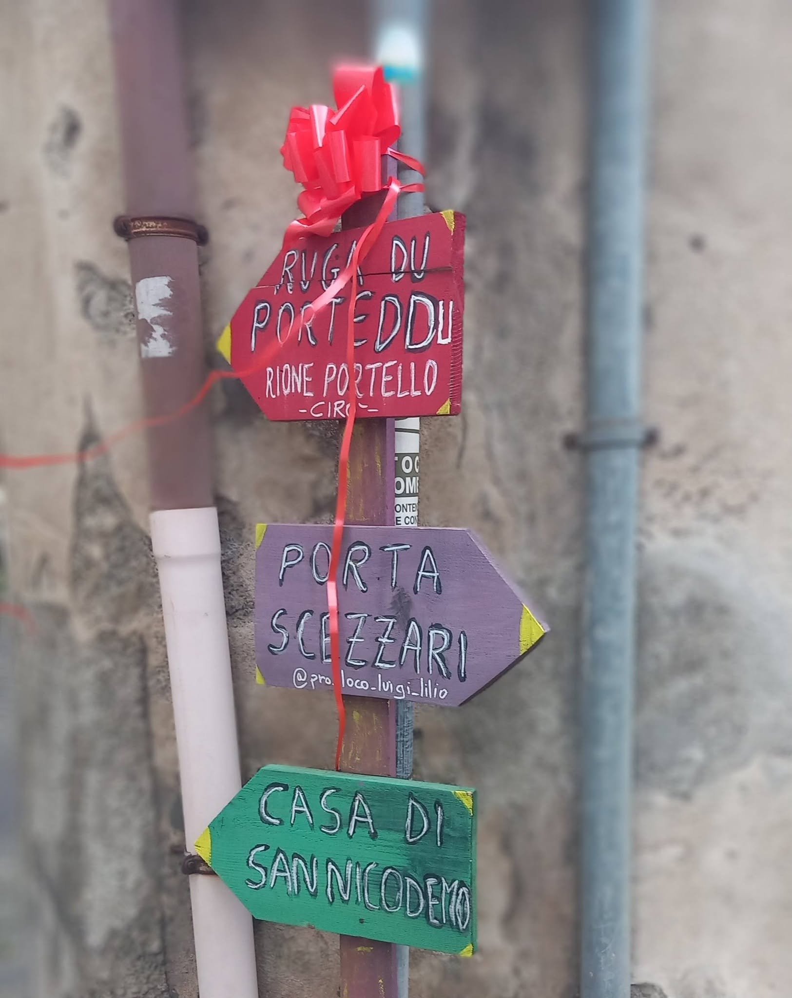 Cartelli direzionali dipinti a mano nel rione Portello di Cirò, tra cui l’indicazione per la Casa di San Nicodemo.